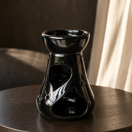 Czarny ceramiczny kominek zapachowy Oyasumi na ciemnym drewnianym stoliku