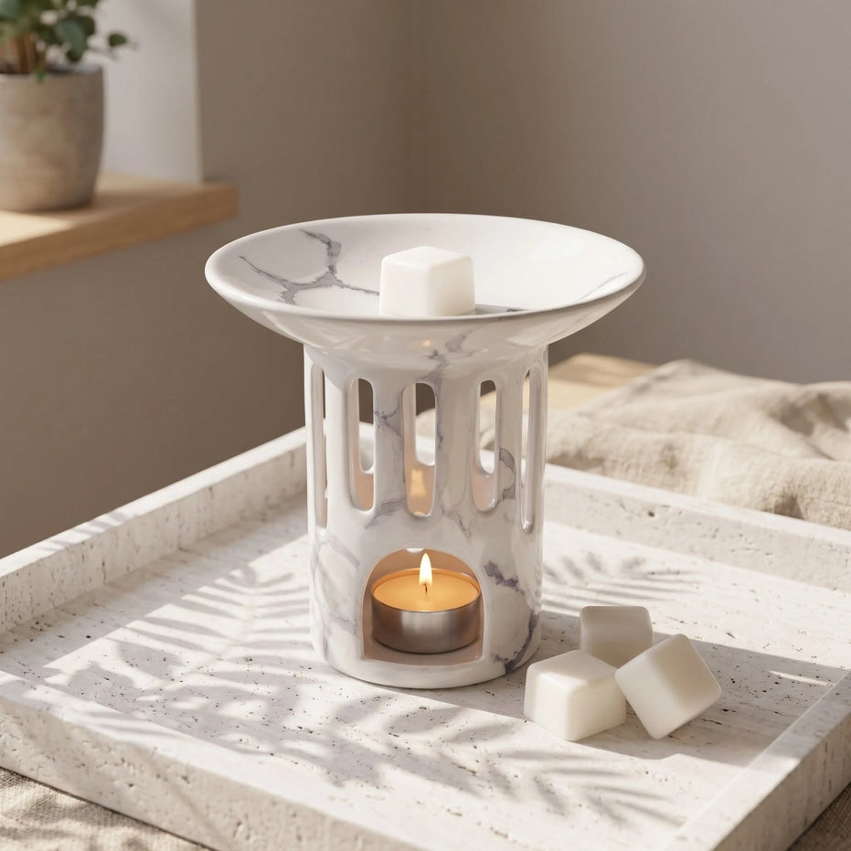 Ceramiczny kominek do wosków zapachowych OYASUMI z marmurkowym wykończeniem, kostkami wosku i świeczką tealight na dekoracyjnej tacy.