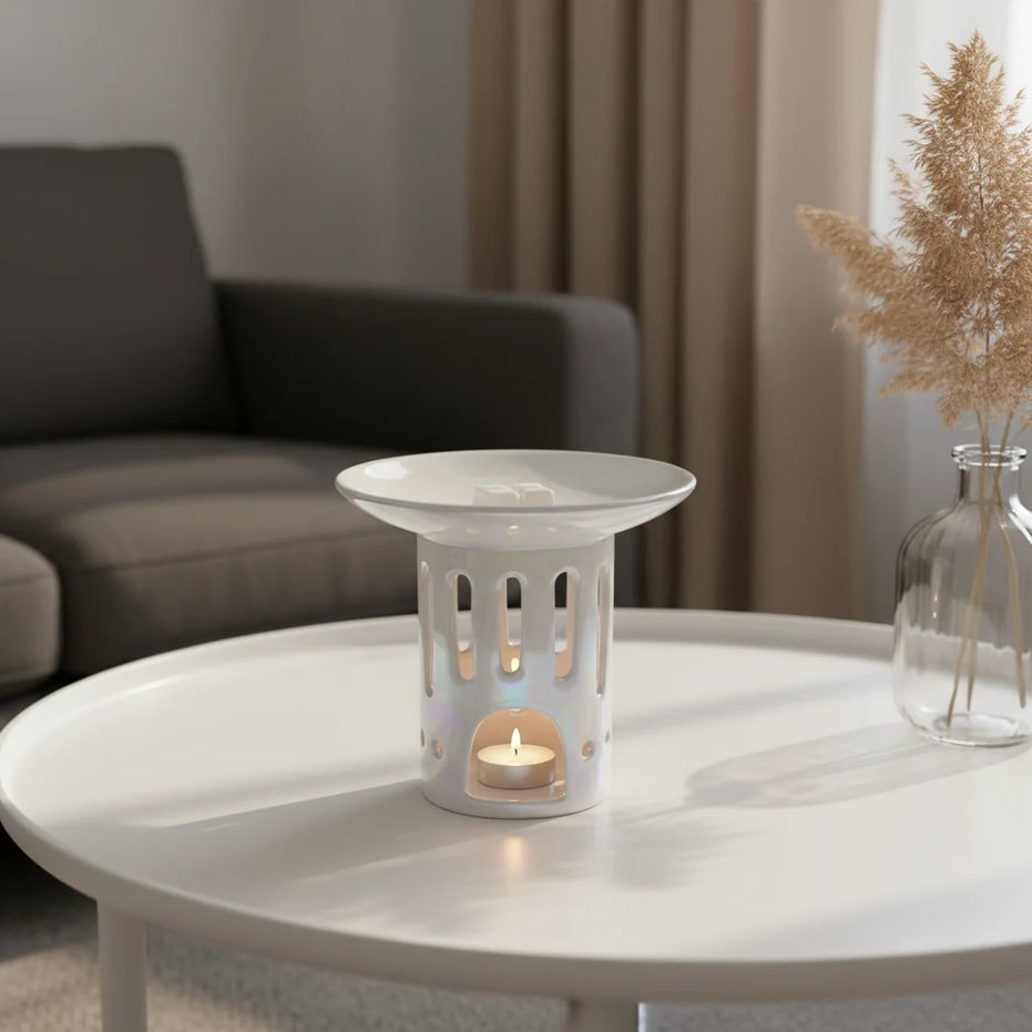 Biały perłowy ceramiczny kominek zapachowy OYASUMI z kostkami wosku oliwkowego i świeczką tealight w eleganckim wnętrzu.