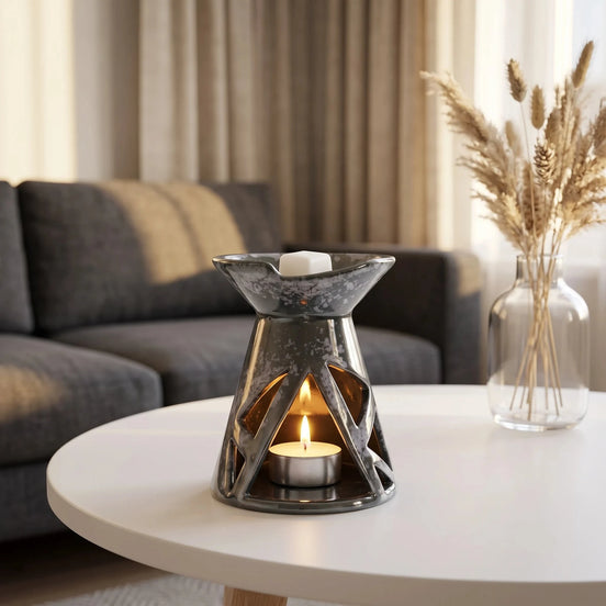 Szary ceramiczny kominek zapachowy OYASUMI z podgrzewaczem tealight i kostką wosku zapachowego na białym stoliku w nowoczesnym salonie.