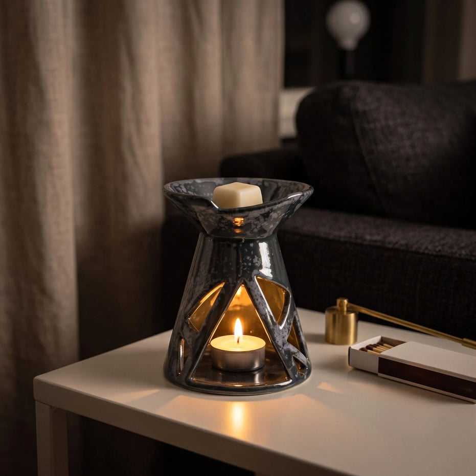 Grafitowy ceramiczny kominek zapachowy OYASUMI z podgrzewaczem tealight i kostką wosku na stoliku podczas wieczornego relaksu.