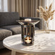 Nowoczesny grafitowy ceramiczny kominek zapachowy OYASUMI z kostką wosku oliwkowego i świeczką tealight w eleganckim salonie.