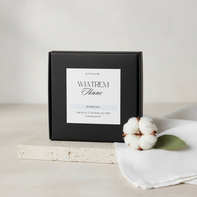 Ekologiczny wosk oliwny Oyasumi obok puszystego kwiatu bawełny na kamiennej podstawce.