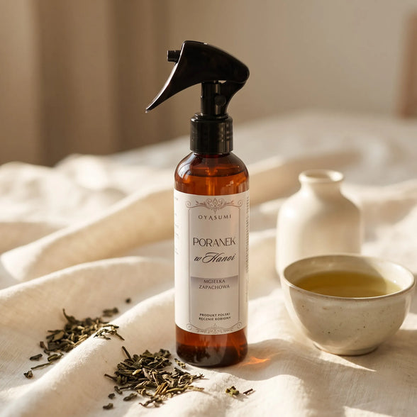 Mgiełka zapachowa Oyasumi Poranek w Hanoi inspirowana aromatem zielonej herbaty, prezentowana z liśćmi herbaty i filiżanką naparu.