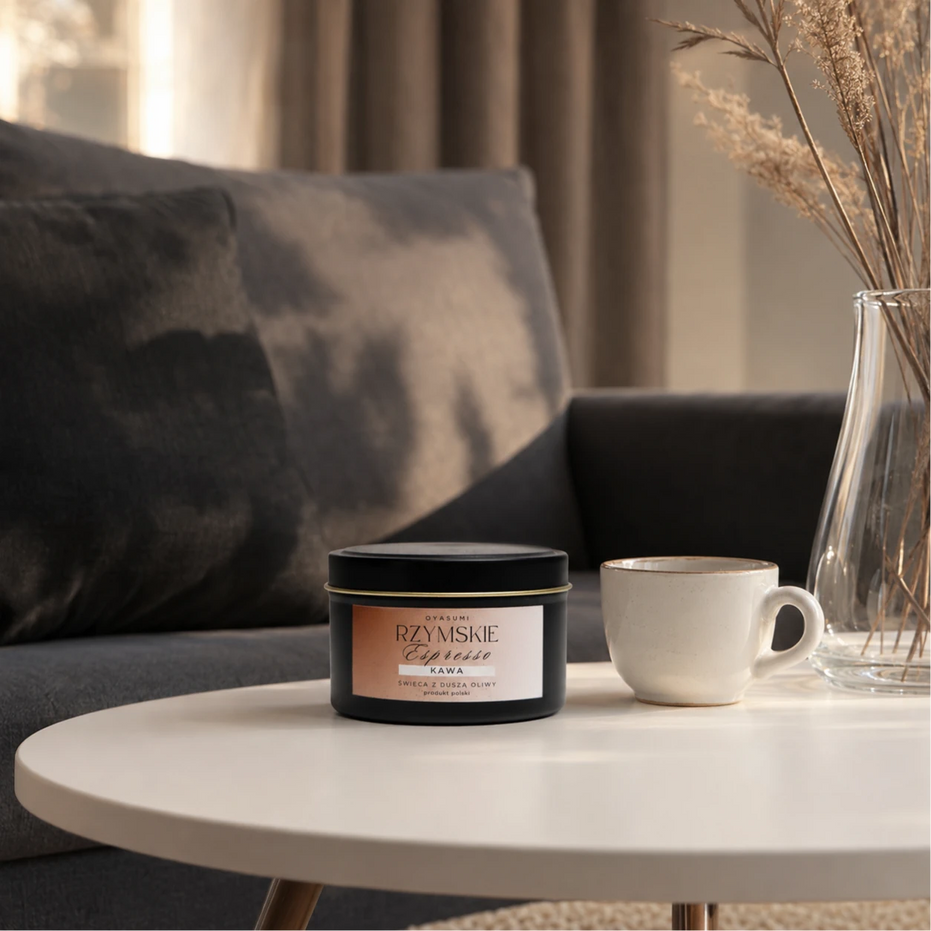 Świeca zapachowa OYASUMI Rzymskie Espresso 90 ml z filiżanką świeżo zaparzonej kawy na białym stoliku kawowym.