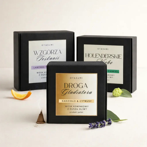 Trzy czarne opakowania wosków oliwnych OYASUMI: Droga Gladiatora, Wzgórza Toskanii i Holenderskie Niebo na jasnym tle obok plastra pomarańczy i lawendy.